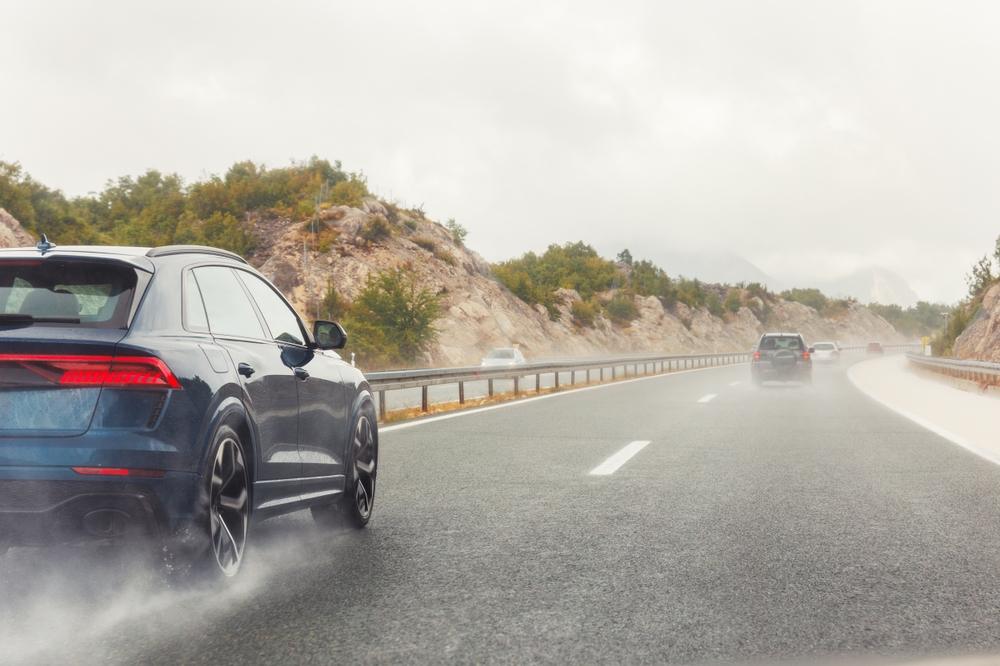 Cars drive down a long highway in the middle of a rainstorm.